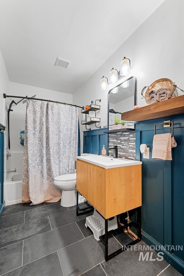 full bathroom featuring toilet, tile patterned floors, vanity, tasteful backsplash, and shower / tub combo