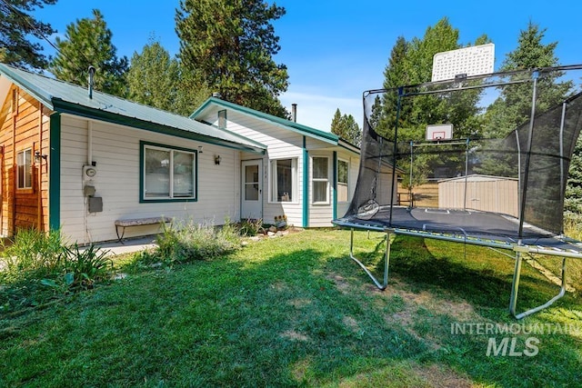 rear view of house with a yard, a storage shed, and a trampoline