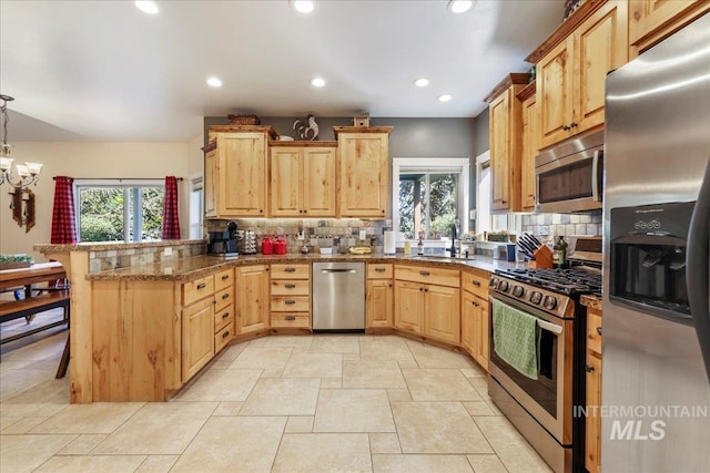 45 Ridge Loop, Jerome, ID 83338 - kitchen featuring appliances with stainless steel finishes, a peninsula, decorative backsplash, light brown cabinetry, and plenty of natural light