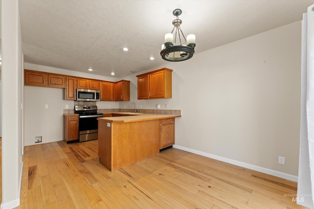 1406 W Wright St, Boise, ID 83705 - kitchen featuring appliances with stainless steel finishes, recessed lighting, a peninsula, brown cabinets, and light wood-style floors