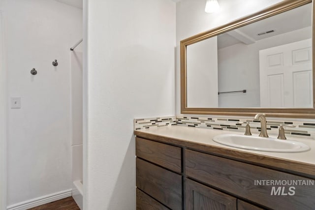bathroom with a shower, vanity, tasteful backsplash, and visible vents