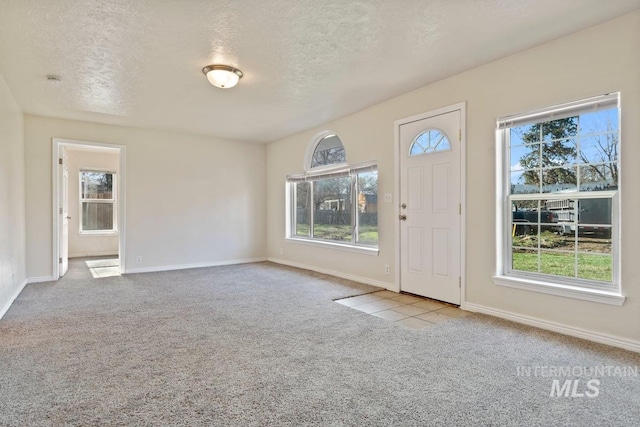 entrance foyer featuring a textured ceiling, a wealth of natural light, and carpet