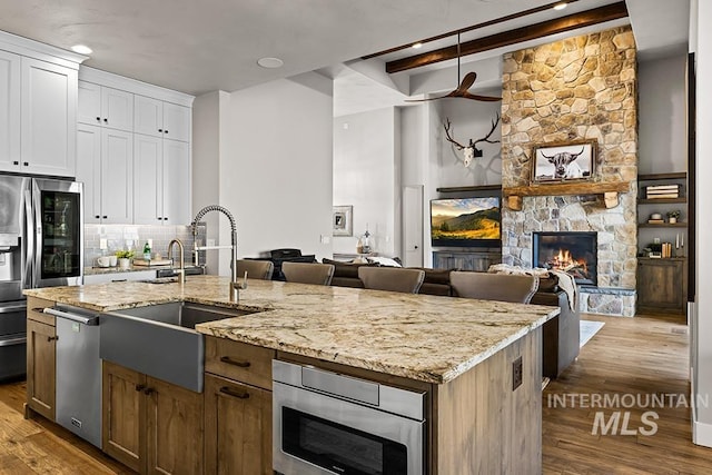 kitchen with wood finished floors, a fireplace, appliances with stainless steel finishes, and a sink