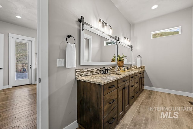 full bath with backsplash, wood finished floors, recessed lighting, double vanity, and baseboards