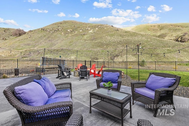 view of patio with an outdoor living space with a fire pit, a fenced backyard, and a mountain view