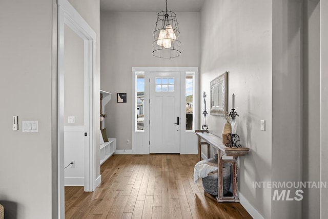 entrance foyer with an inviting chandelier, a high ceiling, baseboards, and wood-type flooring