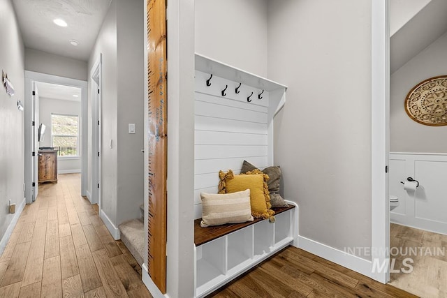 mudroom featuring wood finished floors, baseboards, and wainscoting