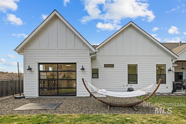 rear view of property featuring a patio, fence, and board and batten siding