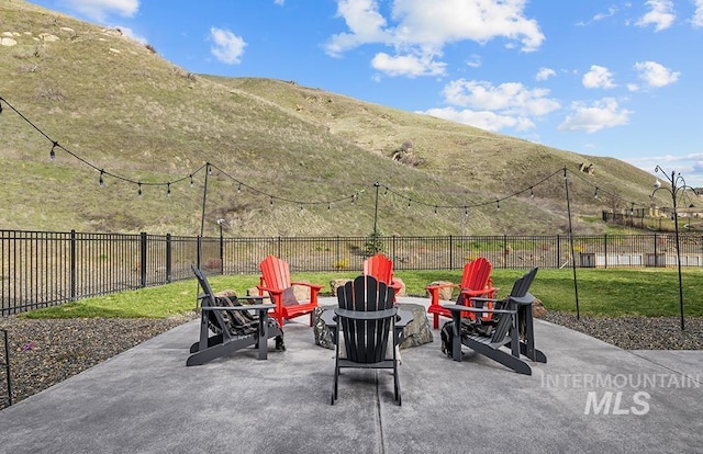 view of patio with a mountain view, a fenced backyard, and an outdoor fire pit