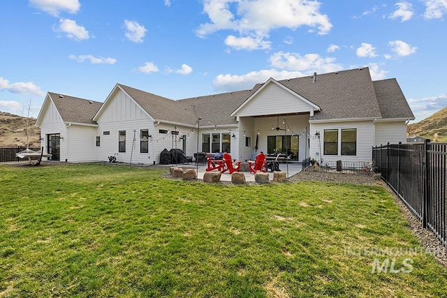 back of house featuring a ceiling fan, a fenced backyard, a yard, board and batten siding, and a patio area