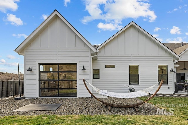 rear view of property with a patio area, board and batten siding, and fence