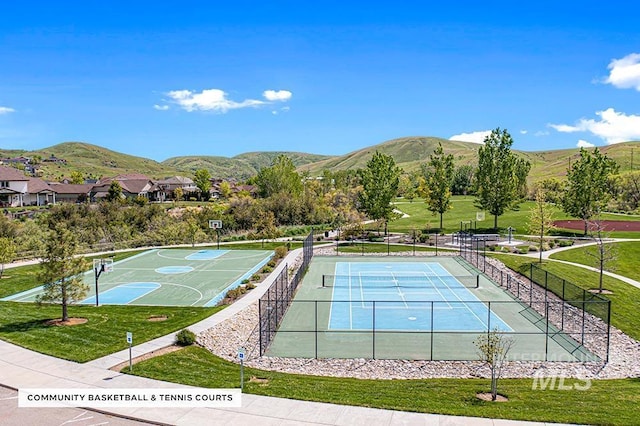 view of sport court featuring community basketball court, a mountain view, a lawn, and fence