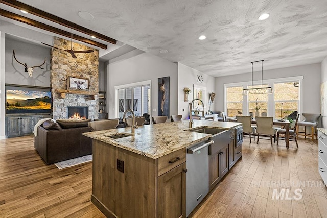 kitchen with dishwasher, a center island with sink, wood-type flooring, and a sink