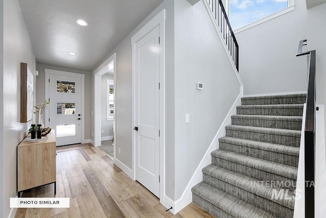 entryway with light wood finished floors, baseboards, recessed lighting, and stairway