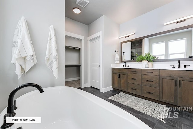 bathroom with a soaking tub, double vanity, a sink, and visible vents