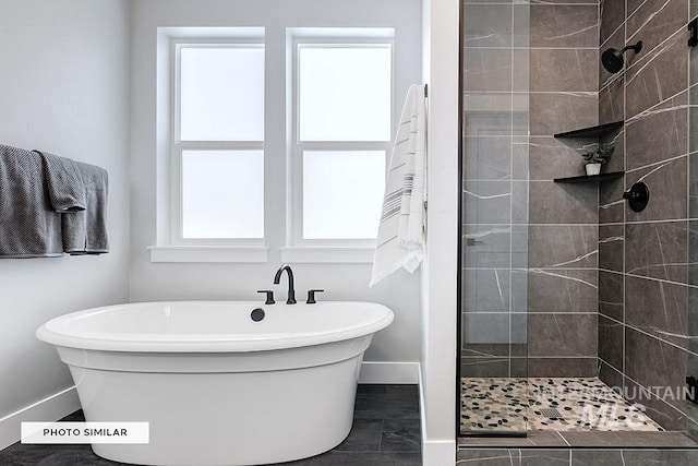 bathroom with a freestanding bath, baseboards, and a tile shower