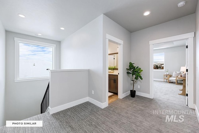 corridor with a wealth of natural light, an upstairs landing, carpet flooring, and baseboards