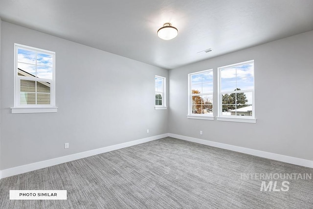 carpeted empty room featuring visible vents and baseboards