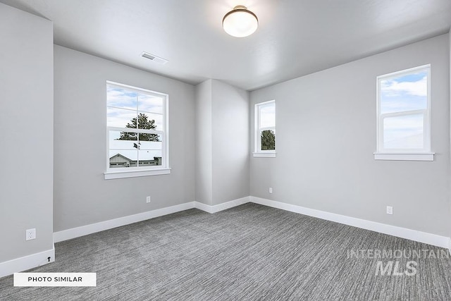 empty room featuring dark carpet, baseboards, and visible vents