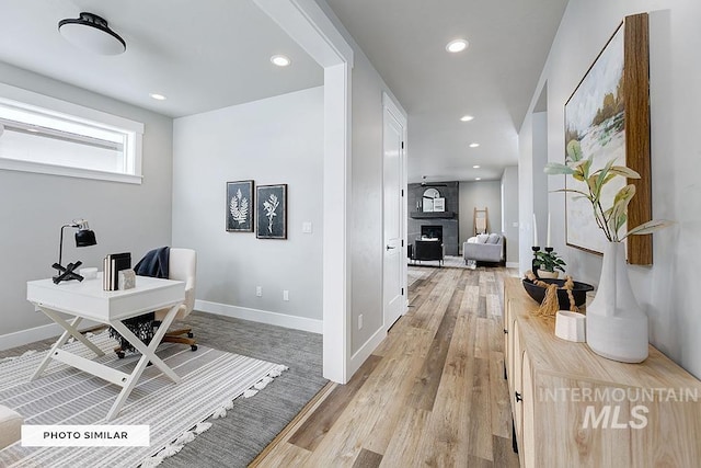 interior space featuring light wood-style flooring, recessed lighting, baseboards, and a fireplace