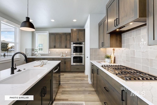 kitchen featuring dark brown cabinetry, recessed lighting, decorative light fixtures, appliances with stainless steel finishes, and a sink