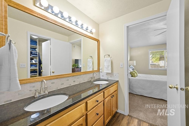 2189 W Rainfall St, Meridian, ID 83646 - ensuite bathroom featuring wood finished floors, tasteful backsplash, double vanity, and a textured ceiling