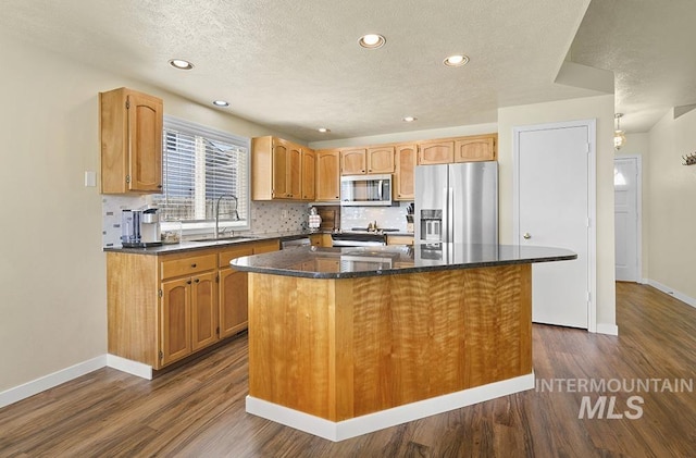 2189 W Rainfall St, Meridian, ID 83646 - kitchen featuring appliances with stainless steel finishes, a sink, a center island, dark wood-type flooring, and baseboards