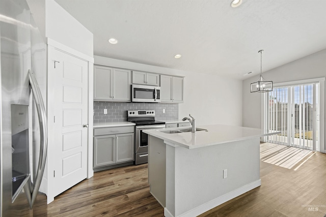 kitchen featuring dark wood-style flooring, gray cabinetry, a sink, appliances with stainless steel finishes, and backsplash