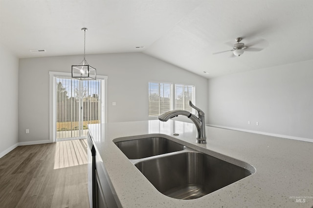 kitchen featuring visible vents, pendant lighting, lofted ceiling, light stone counters, and a sink