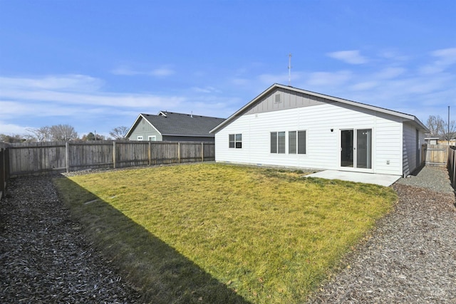 back of house with a yard, a patio, board and batten siding, and a fenced backyard