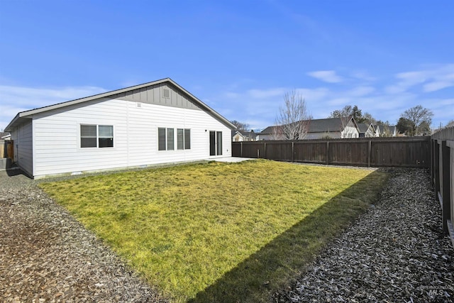 back of property with a patio, a lawn, board and batten siding, and a fenced backyard