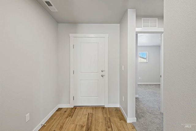 corridor featuring wood finished floors, baseboards, and visible vents