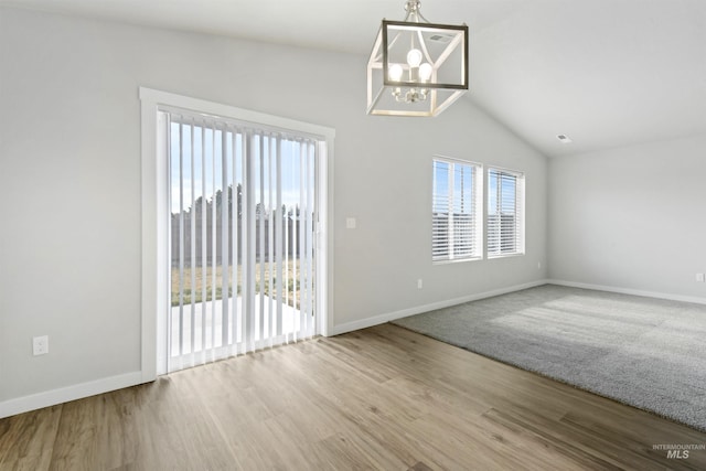 spare room featuring baseboards, lofted ceiling, an inviting chandelier, and wood finished floors