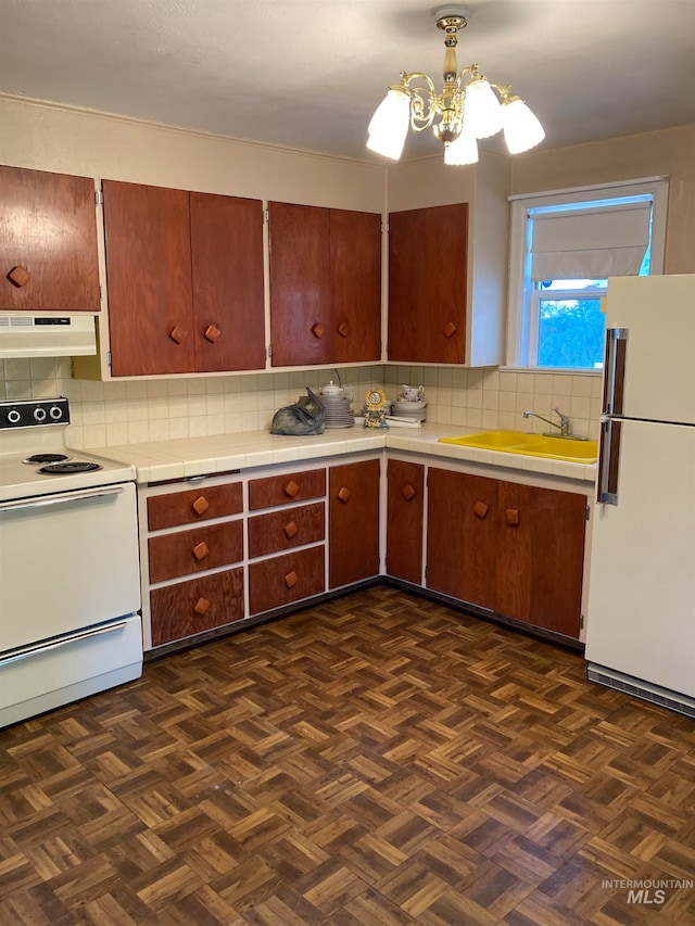 kitchen featuring sink, backsplash, white appliances, decorative light fixtures, and dark parquet flooring