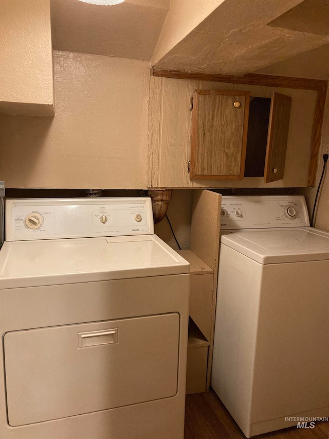 laundry room featuring cabinets, dark hardwood / wood-style floors, and washing machine and dryer