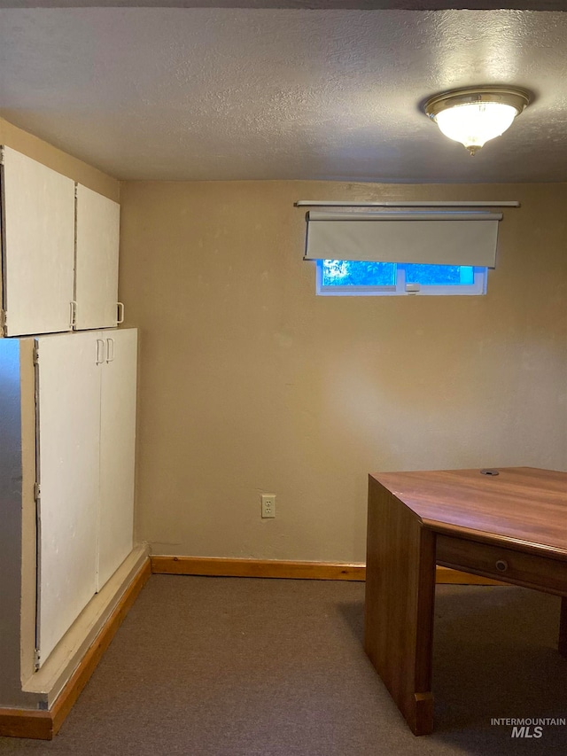 interior space with a textured ceiling and dark colored carpet