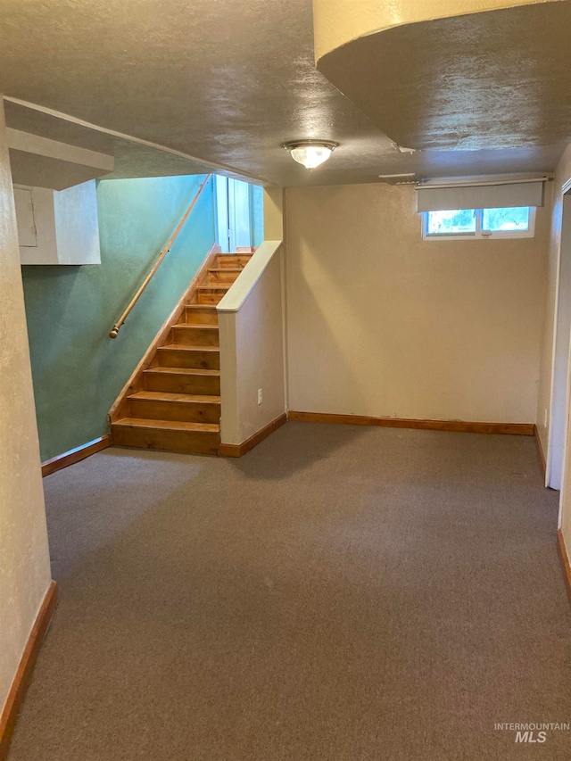 basement featuring a textured ceiling and carpet flooring