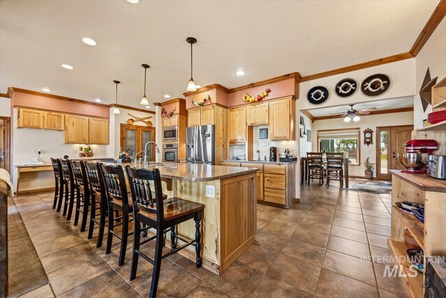 1770 N 3rd St, Nyssa, OR 97913 - kitchen with stainless steel appliances, ornamental molding, a ceiling fan, a center island with sink, and a kitchen bar