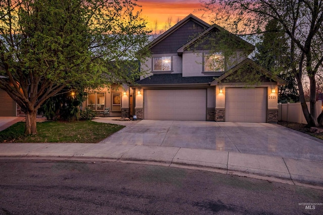 craftsman-style home featuring a garage, fence, stone siding, and stucco siding