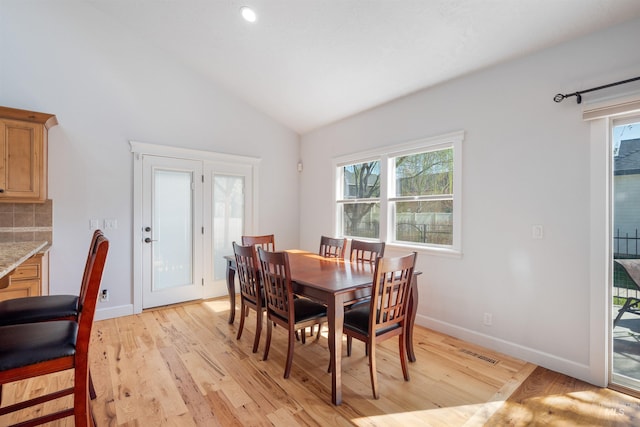 dining room with light wood-type flooring, lofted ceiling, visible vents, and a wealth of natural light