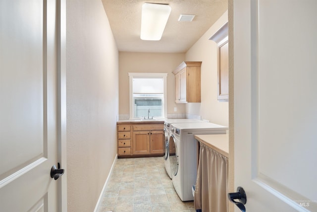laundry area featuring visible vents, washing machine and clothes dryer, a sink, baseboards, and cabinet space