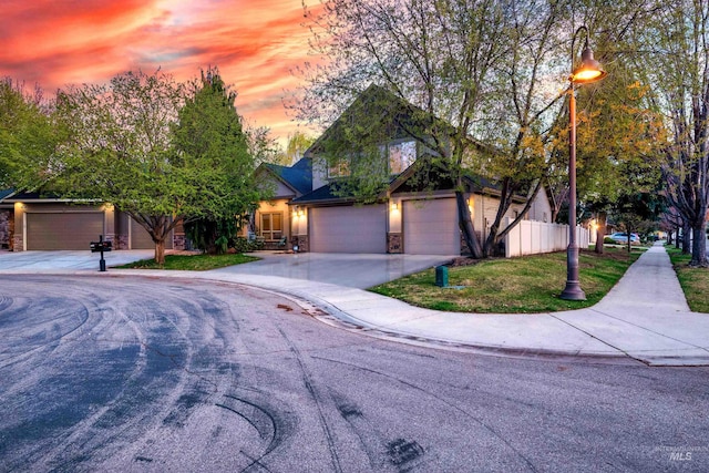 view of front facade with an attached garage, fence, stone siding, and concrete driveway