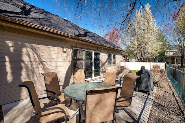 wooden deck featuring outdoor dining space, a patio area, and a fenced backyard