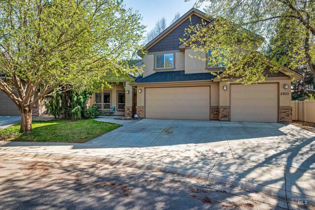 craftsman inspired home featuring a garage, driveway, stucco siding, and stone siding