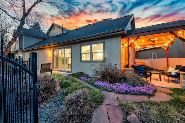 back of house at dusk featuring a patio, outdoor lounge area, and fence