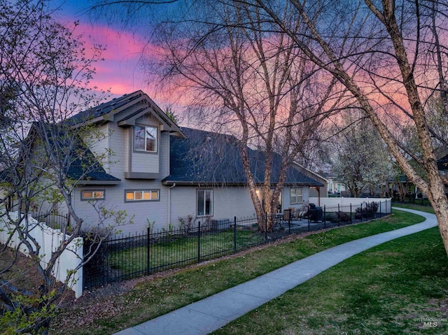 view of front of home featuring roof with shingles, a lawn, and a fenced front yard