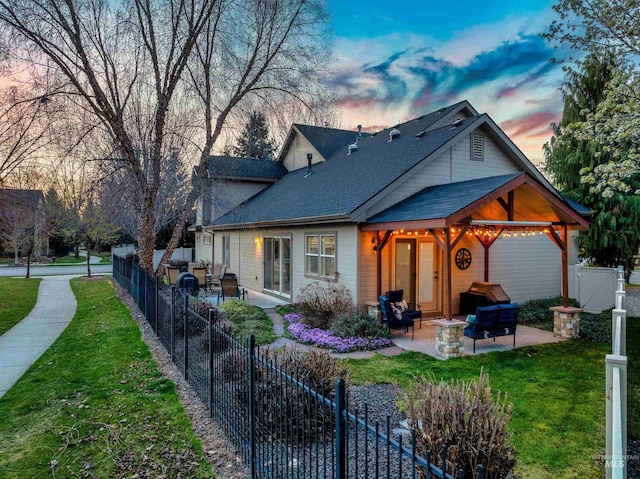 back of property with a patio area, a fenced backyard, a shingled roof, and a yard