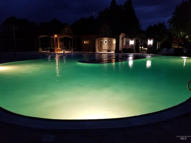 pool at night featuring a community pool