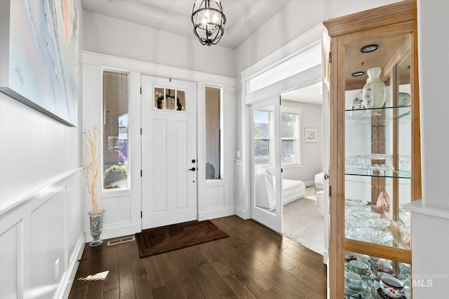 foyer entrance with an inviting chandelier and dark wood-type flooring