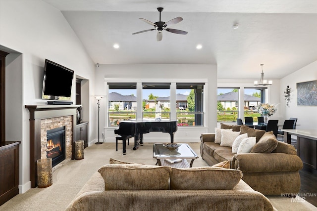 living room with light colored carpet, ceiling fan with notable chandelier, a stone fireplace, and lofted ceiling